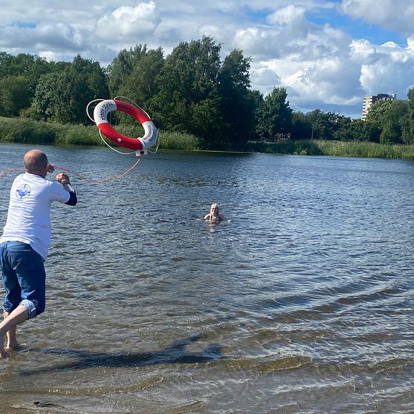 Jonny Darabant, vice ordförande i SLS Sörmland, kastar ut en livboj från en strandkant ut till en flicka som befinner sig i sjön.