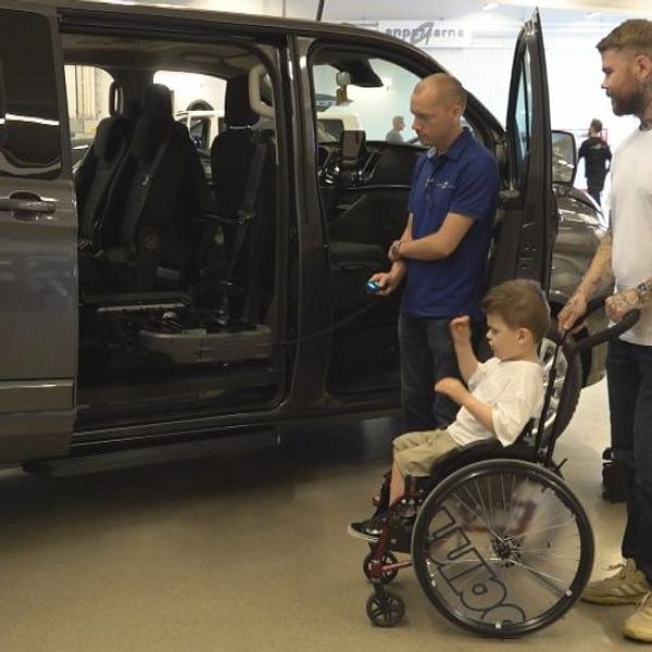 en lite pojke i rullstol, hans pappa, och en man från bilverkstaden tittar på en minibuss med öppen sidodörr