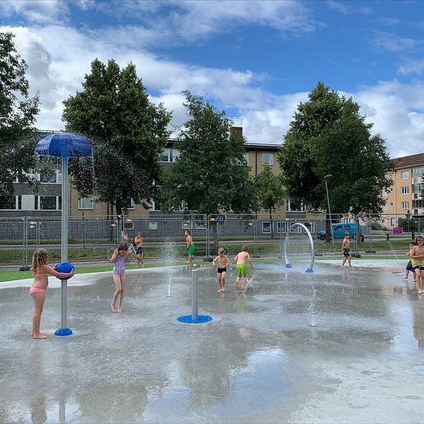Barn leker vid sprayduschar i en vattenlekpark i Sveaparken i Katrineholm.