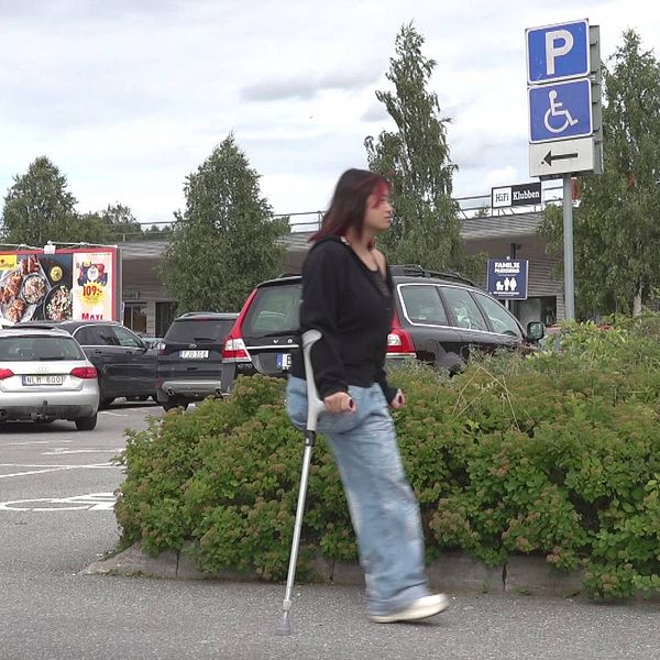 En tjej med ett ben hoppar på kryckor på en parkering i Umeå.