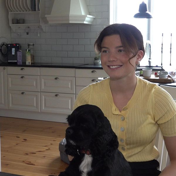 tjej som sitter i ett kök med en hund i knät