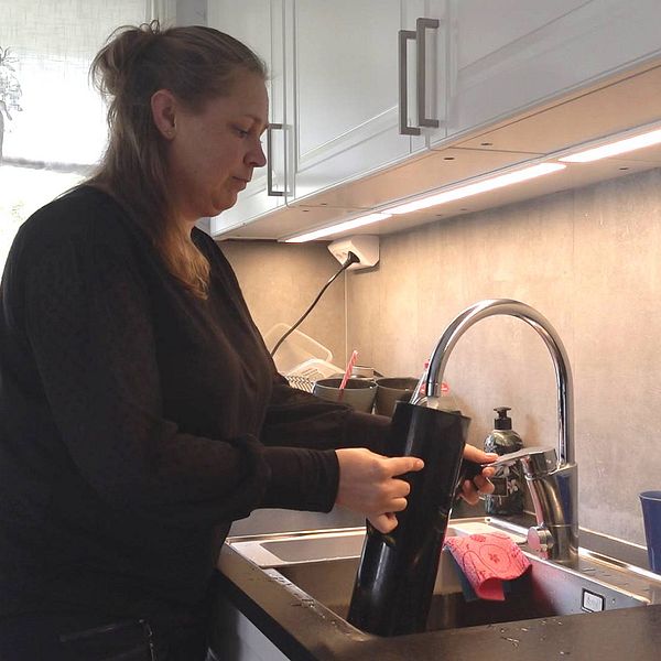 En medelålders kvinna fyller på vatten i en kaffekokare.