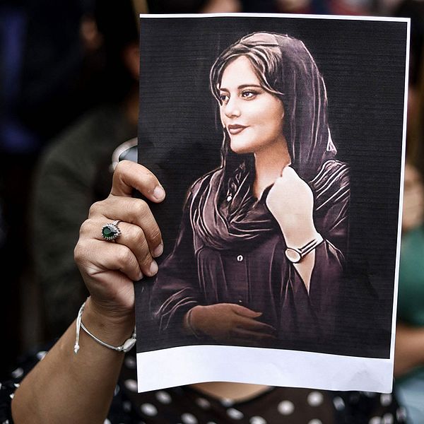 En demonstrant håller upp en teckning av Mahsa Amini.