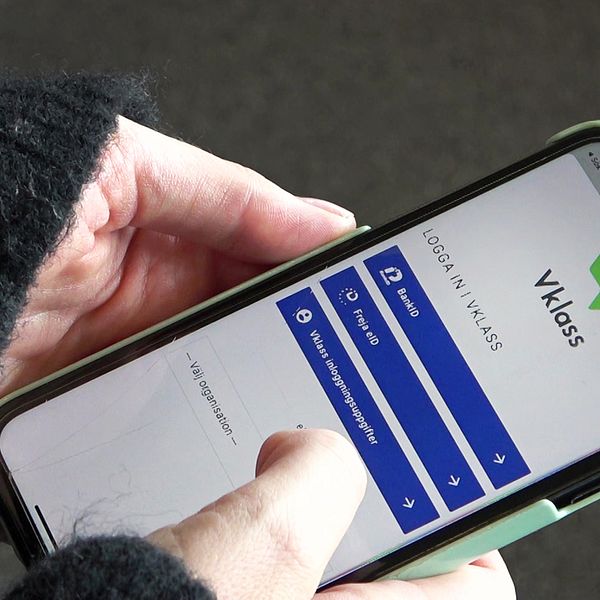 En hand som håller i en mobiltelefon med Vklass på.