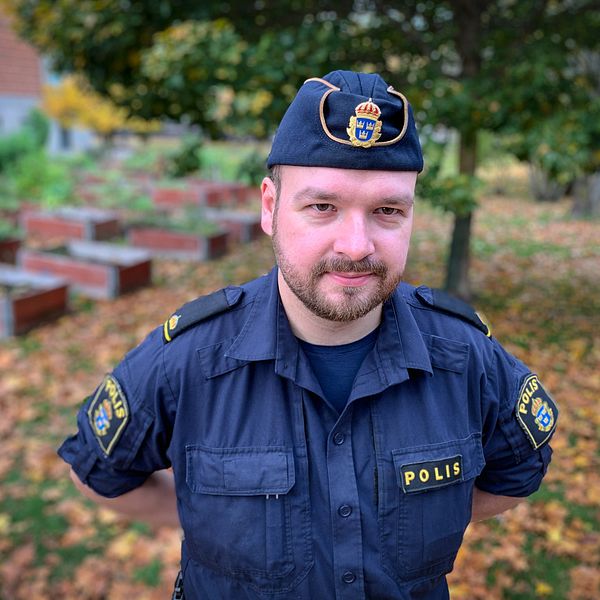 porträttbild på polisen Benjamin Sjöberg – en man polisuniform och polismössa, utomhus på hösten