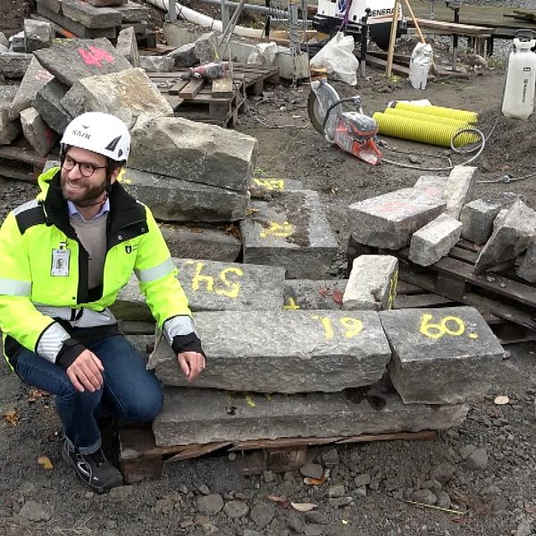 Byggprojektledaren Kristian Gullner sitter bredvid stenblock med siffror på