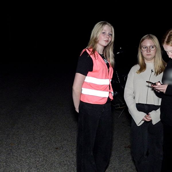 Fyra unga tjejer som står på en mörk gata.