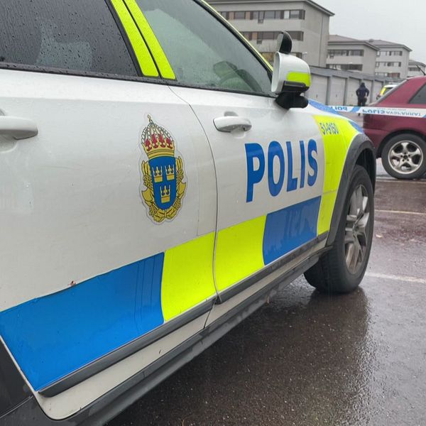 Bild på polisbil och poliser framför garageportar i Gårdsten i Göteborg. Polisen har där spärrat av ett bostadsområde efter att en man hittats medvetslös och skjuten i en bil under tisdagsmorgonen.