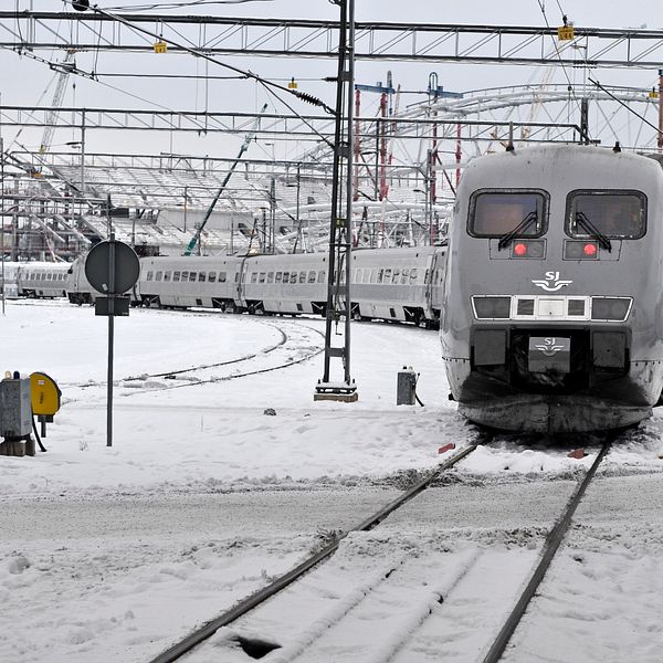 Ett tåg står inne på en snöig bangård.