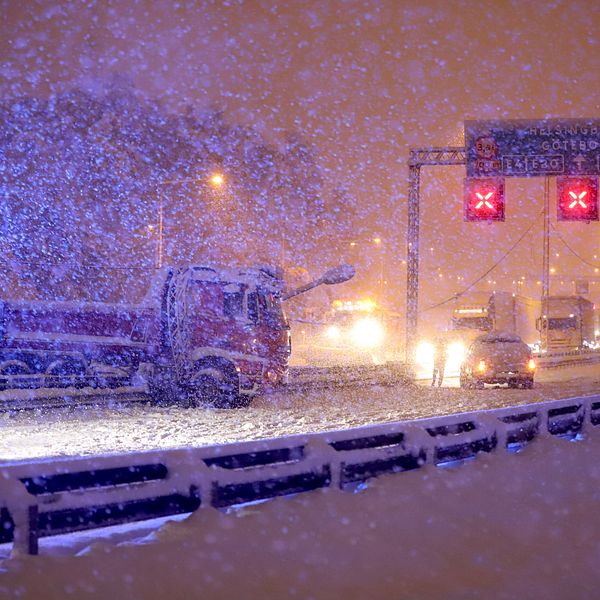 Bilar står i kö medan ett kraftigt snöfall skapar ett tjockt snötäcke.