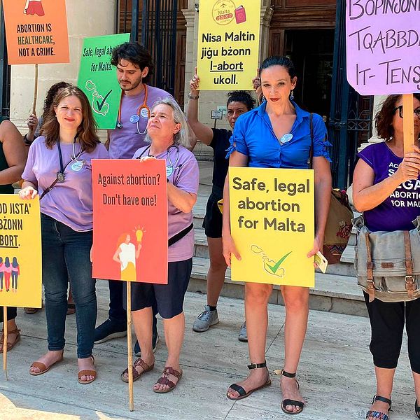demontranter med skyltar som protesterar mot Maltas abortlagar