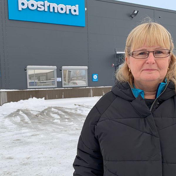 Kvinna med mörk täckjacka, ljust hår, glasögon, står utanför Postnords lokaler i Borlänge. Katarina Sörman, distributionsområdeschef för Dalarna.