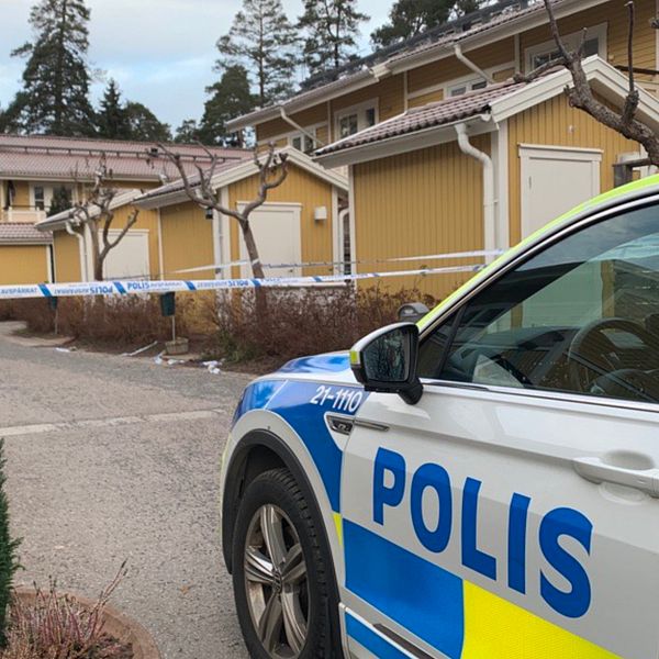 En polisbil med hus i bakgrunden.