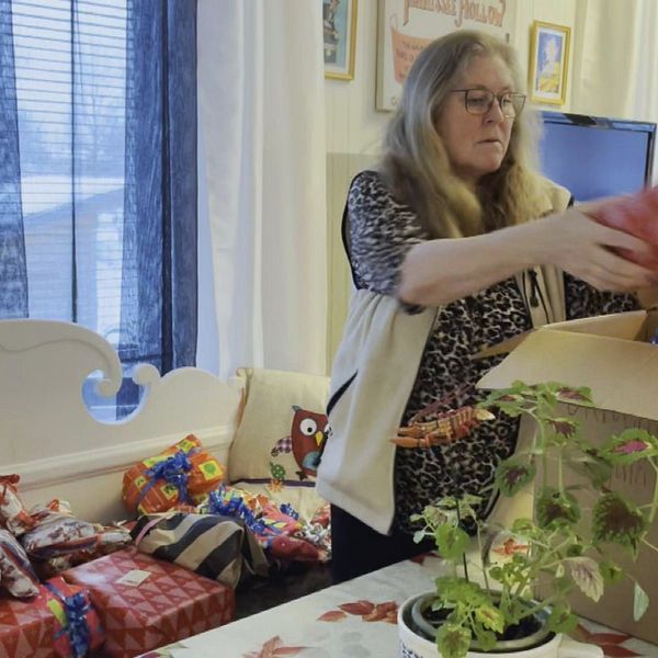 Evy Ohlsson, en kvinna med långt hår och glasögon, packar julklappar i en kartong som ska skickas till Ukraina.