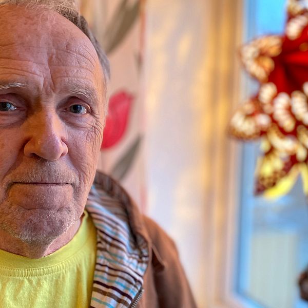 Porträttbild på Eskilstunabon Terje Lindberg, en man i 65-årsåldern. Han tittar in i kameran. I bakgrunden syns ett fönster med en röd julstjärna som lyser.