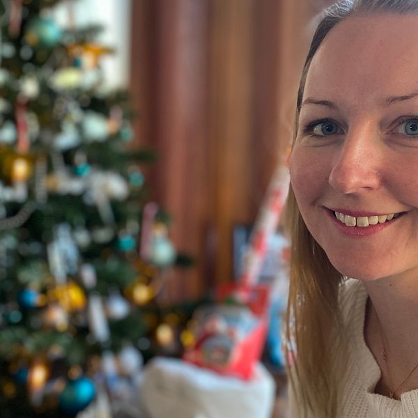 Bild på Eskilstunabon Jannica Sjöstedt. Hon har rågblont hår och tittar in i kameran. I bakgrunden skymtar en julgran som det ligger julklappar under.