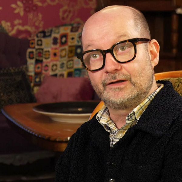 Jonas Wihlstrand, generalsekreterare för Riksföreningen Sveriges Stadsmissioner, sitter i en soffa. Han har glasögon och skjorta och tröja.