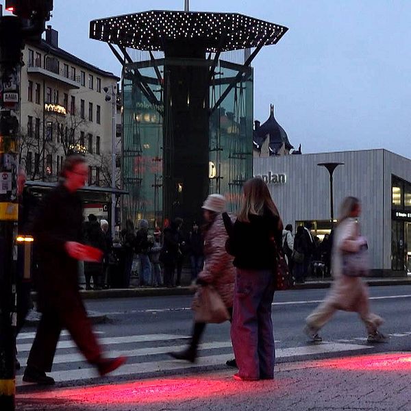 Fotgängare går mot rött ljus vid det bevakade övergångsstället Odenplan i centrala Stockholm.