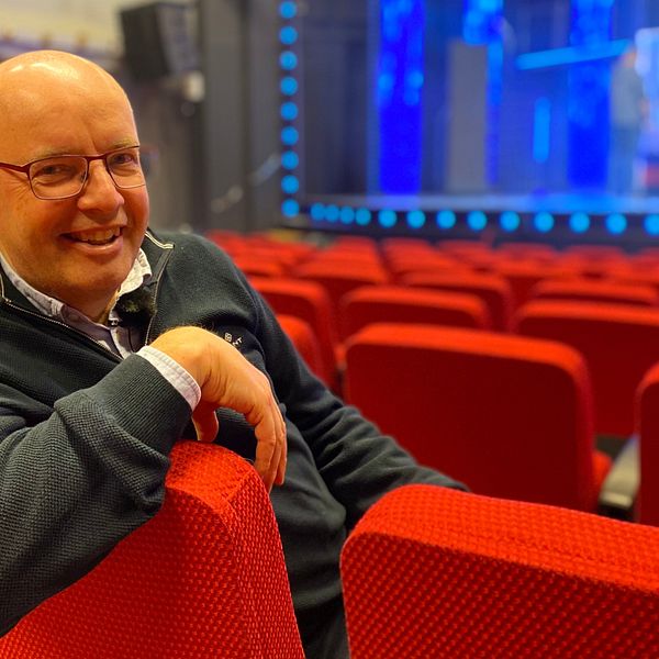 Bild på en man med glasögon som sitter i en röd teaterstol i en salong. Mannen heter Magnus Wernersson och är oroducent på Falkenbergsrevyn. I klippet får vi se bilder från den nya revyn.