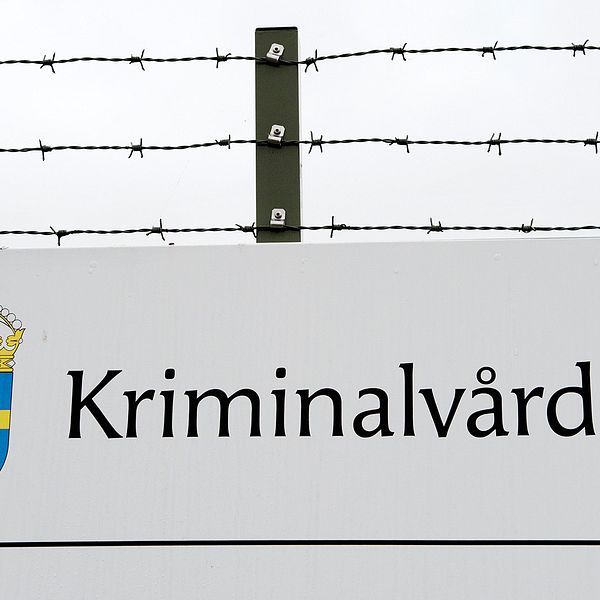 Exteriörbild på ett staket med Kriminalvårdens skylt.