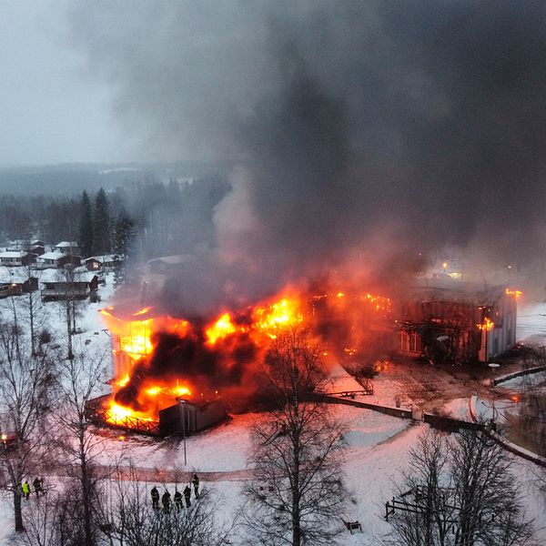 En stor träbyggnad står i brand.