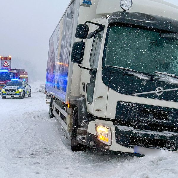 En lastbil i snön, står lite lutad mot mitträcket på E6