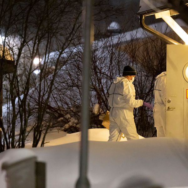 Bilden visar när personer iklädda vita skyddskläder och munskydd går in i ett hus med skylten ”Avspärrat” på dörren, i samband med mordet på 8-åriga Tintin i Luleå.