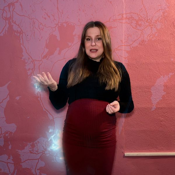 SVT:s reporter Johanna Holstein står framför en rosatonad kara som visar södra Sverige och delar av Danmark.