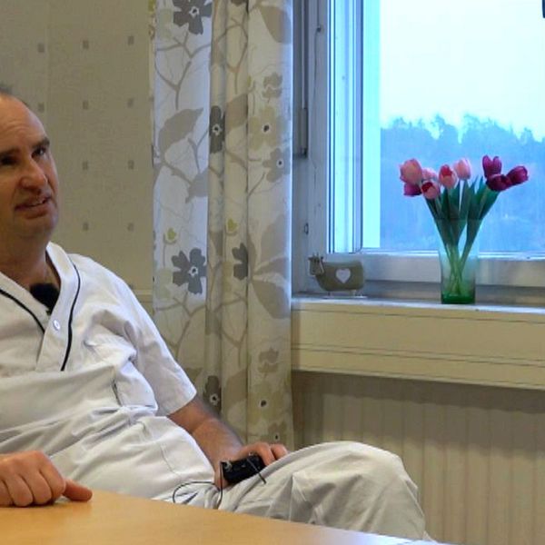 Bild på en man i vita läkarkläder som sitter lutad mot ett bord i ett rum vid ett fönster med tulpaner. Mannen heter Marcus Lind och är professor i diabetolog vid Göteborgs universitet. Han är med i en studie om diabetes.