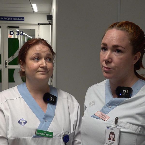 Två kvinnor iklädda sjukhuskläder står bredvid varandra i en sjukhusmiljö.