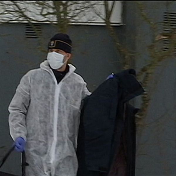 En kriminaltekniker bär ut ett klädesplagg från platsen där mordet ska ha ägt rum.