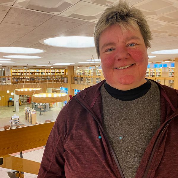 En leende kvinna i kort, ljust hår tittar in i kameran. Hon befinner sig på övervåningen i Faluns bibliotek.