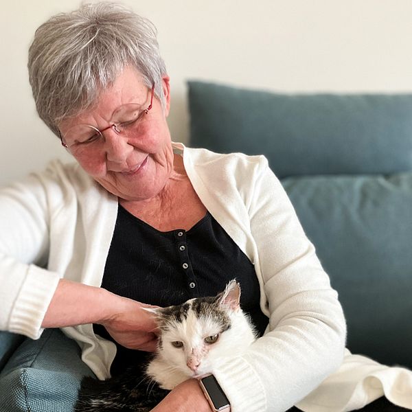 En bild på en kvinna som sitter i en soffa med en katt i knät. Kvinnan heter Helvi Frengen och katten heter Boris.