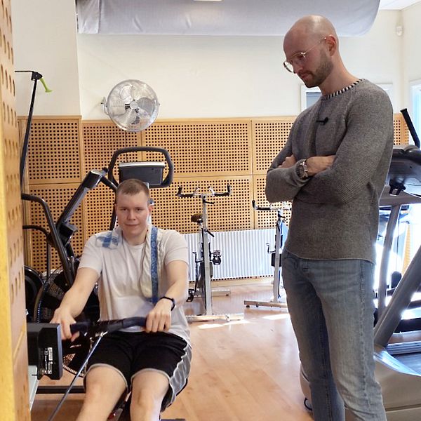 Dennis Carlsson tränar med hjälp av sin assistent på ett gym i Örkelljunga.