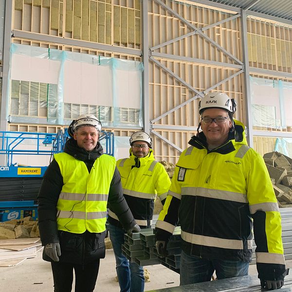 Tre män, Andreas de Jounge, fastighetschef på Uppsala Akademiförvaltning, Niclas Ahlm, projektchef och Jan Person, produktionschef på entreprenaden, i gula västar står framför en stor vägg med reglar.