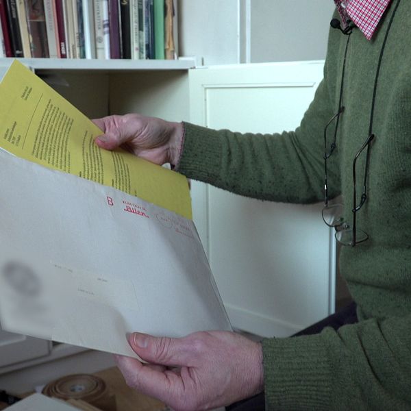 Ett brev med gult papper inuti landar in i en mans brevlåda.