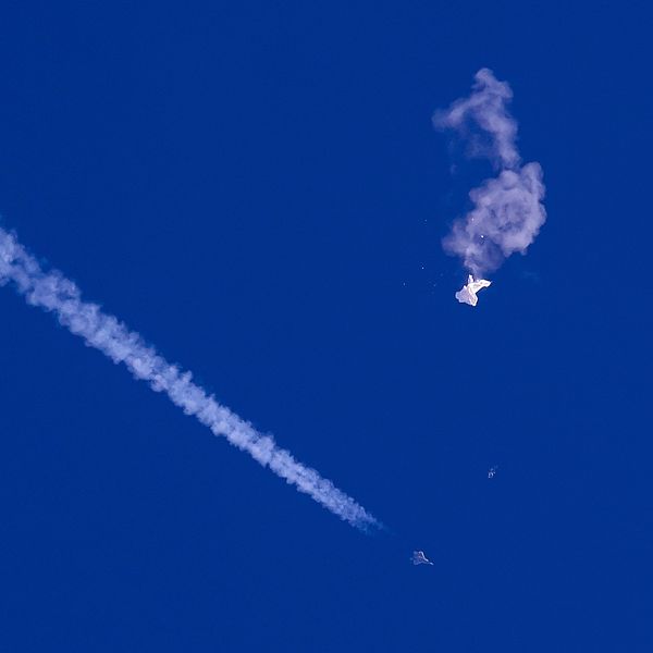 En vit ballong mot en blå himmel singlar punkterad ner mot marken.