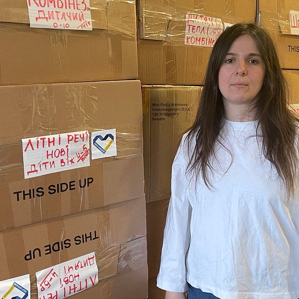 Läkaren Katja Blagodyr står bredvid lådor med barnkläder och leksaker som ska till barnhem i Ukraina