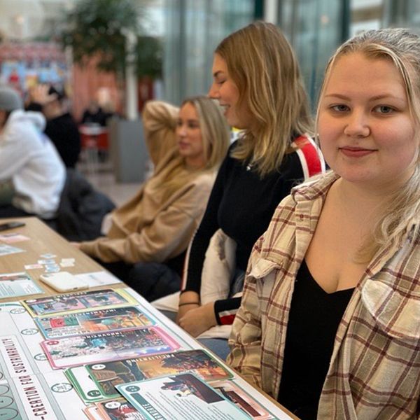 Studenten Kjerstin Dalbert sitter inne i Karlstads universitets byggnad med andra studenter runtomkring sig.