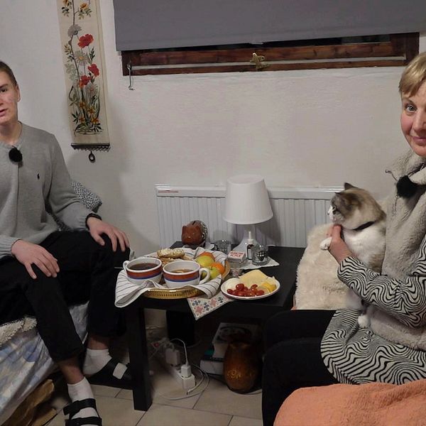 Ukrainska Tymofii Gorpynych och hans mamma Nataliya sitter i sin lilla lägenhet utanför Vellinge. Bordet är dukat med fika och mamman har en katt i famnen.