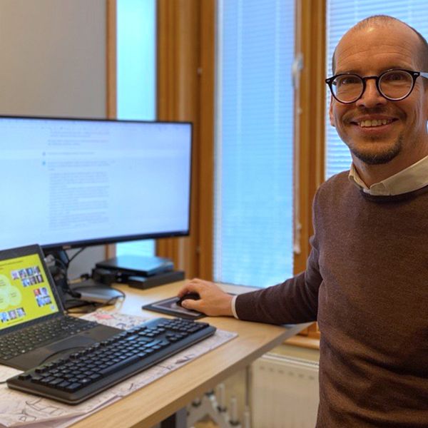 Lektorn Jörg Pareigis på Karlstads universitet står vid datorskärmar och ler in i kameran.