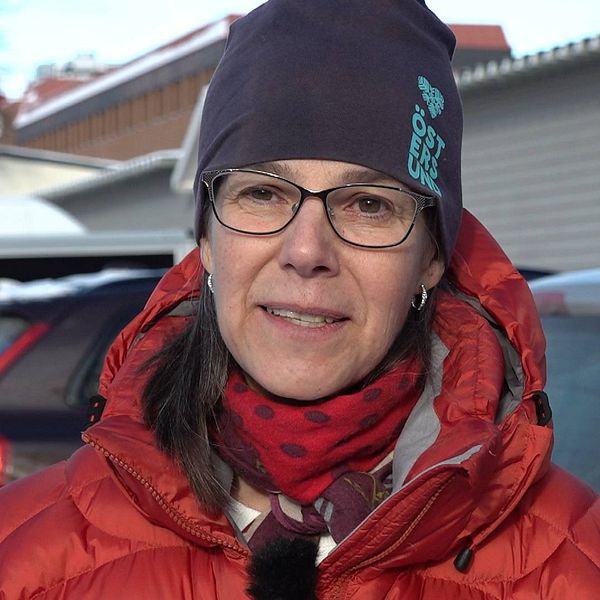 Miljöchefen i Östersunds kommun, Ann-Charlotte Skoog, menar att det är av yttersta vikt att minska biltrafiken i centrum. På bilden ser man Ann-Charlotte Skoog, klädd i röd täckjacka och en blå mössa. Hon har metallbågade glasögon.