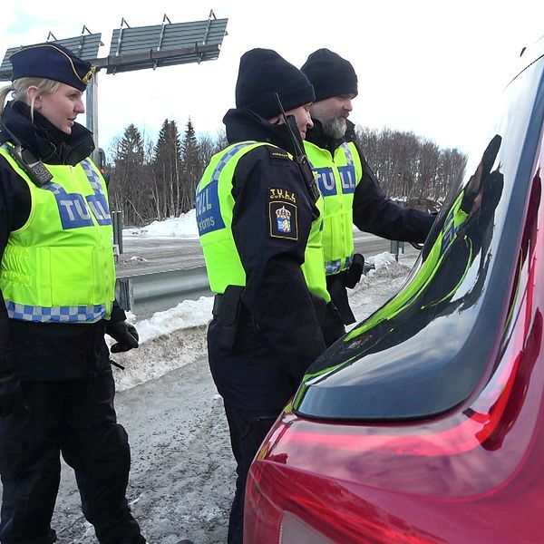 Tre personer i tullens uniform och reflexväst pratar med en bilförare vid tullstationen i Storlien, vintertid