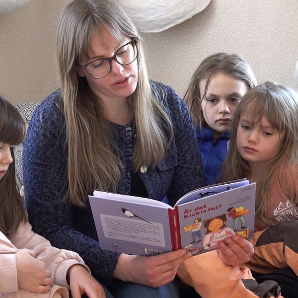 Författaren Sofia Sköld läser sin bok med titeln ”Är det Kickis fel?” för barn som sitter runt henne i en soffa.