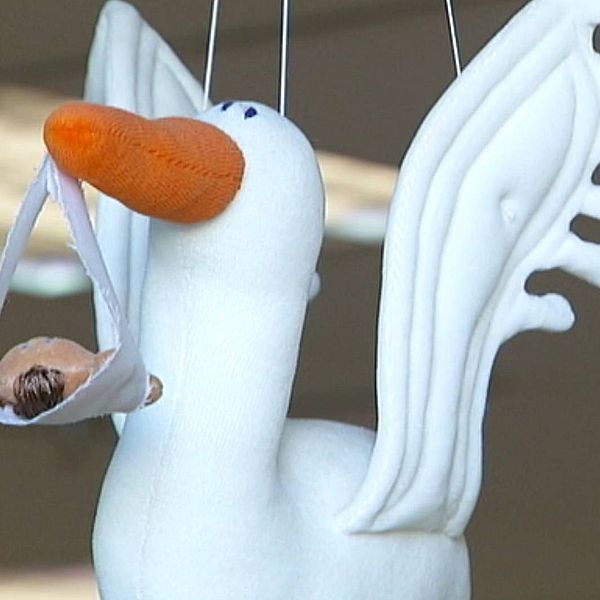 Bild på ett mjukisdjur föreställande en stork. I näbben hänger en docka. Ska symbolisera födsel.