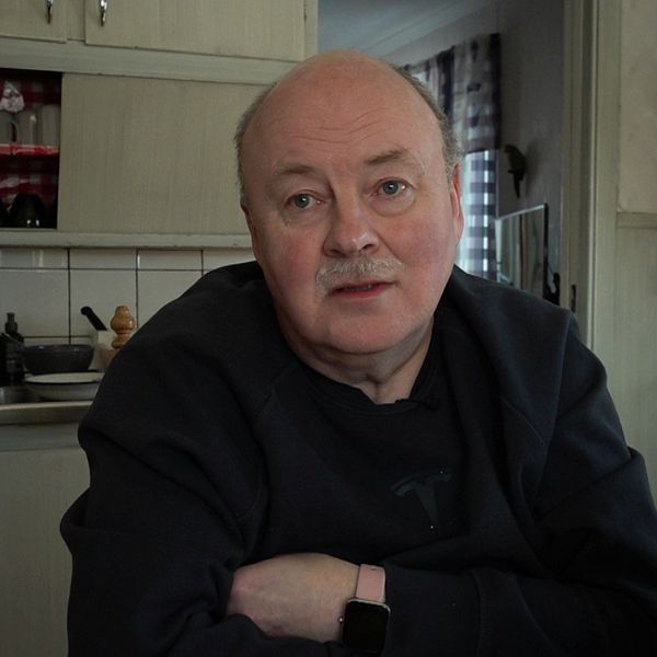 Mikael Ivarsson, en man med mustasch sitter i sitt kök i Tandsbyn med korslagda armar
