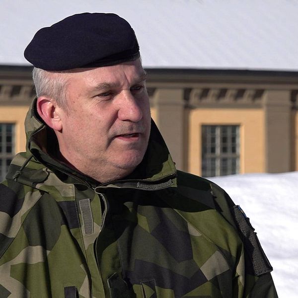 Man i militärkläder står utomhus. Det är snö och i bakgrunden syns en gulbrun byggnad.