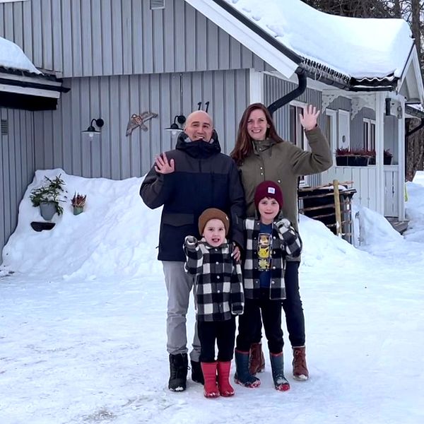 en familj med en pappa, en mamma och två barn, som står i vinterkläder i snön utanför sitt hus i Malå, de vinkar och ser glada ut