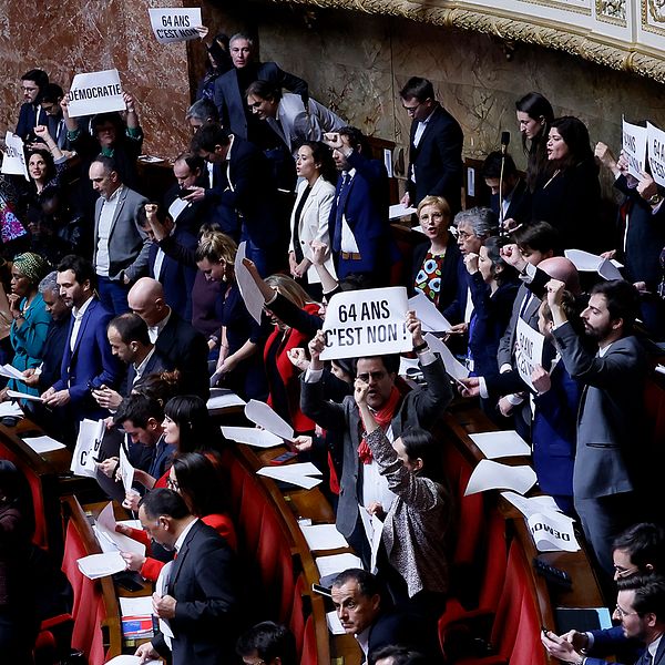 Franska parlamentet håller i plakat och sjunger.