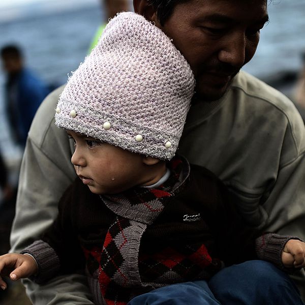 En afghansk flykting anländer till den greksika ön LEsbos med sitt barn i famnen.